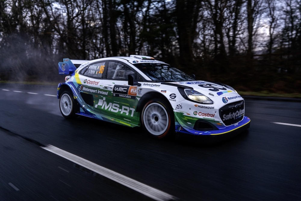 M-Sport Ford Puma Rally1 55 on a wet tarmac road throwing up spray as it speeds past leafless trees during testing ahead of the WRC season and Rallye Monte Carlo