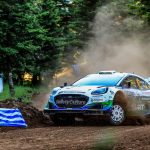 Jon Armstrong and Shane Byrne power their M-Sport Ford Puma Rally1 through a dusty forest gravel stage past a Greek flag at Acropolis Rally Greece 2026