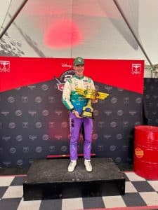 Jon Armstrong holds a trophy on the podium at the Disney Pixar Cars display, Goodwood Festival of Speed 2026